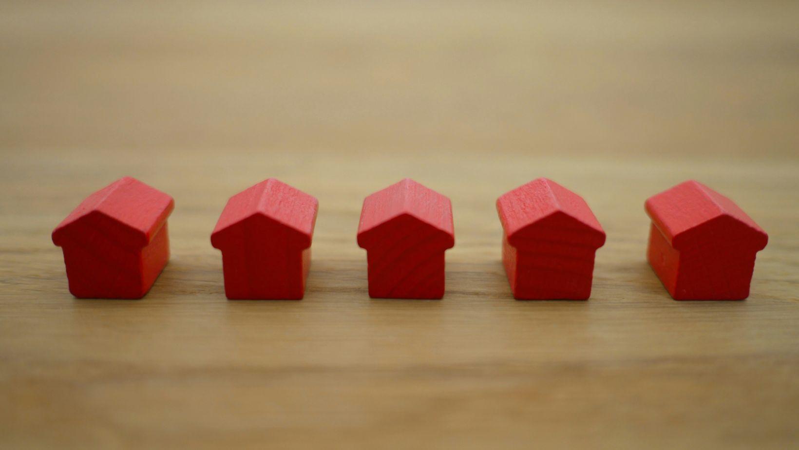 Miniature house model beside a magnifying glass, representing a home sale search